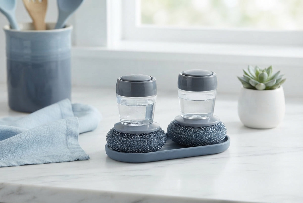 Two 2-in-1 liquid soap dispensing brushes placed on a white kitchen counter with blue decor accents.